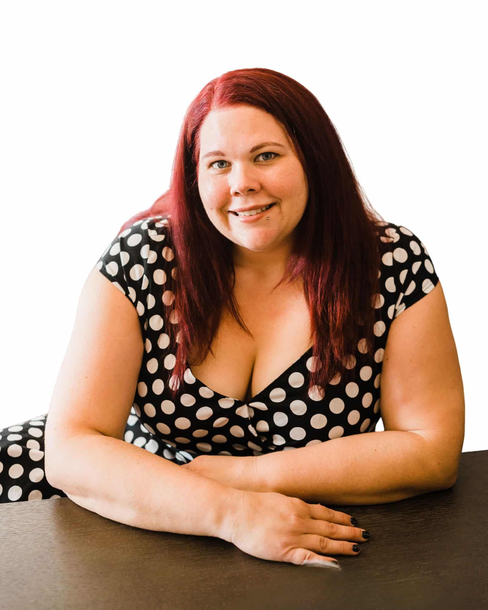Kassandra Williams, owner of Oak City Admins, smiling at desk in polka dot dress